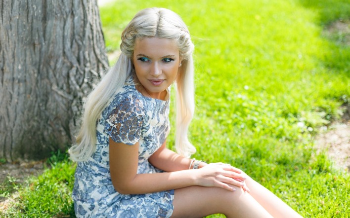 девушка блондинка у дерева на траве лужайка