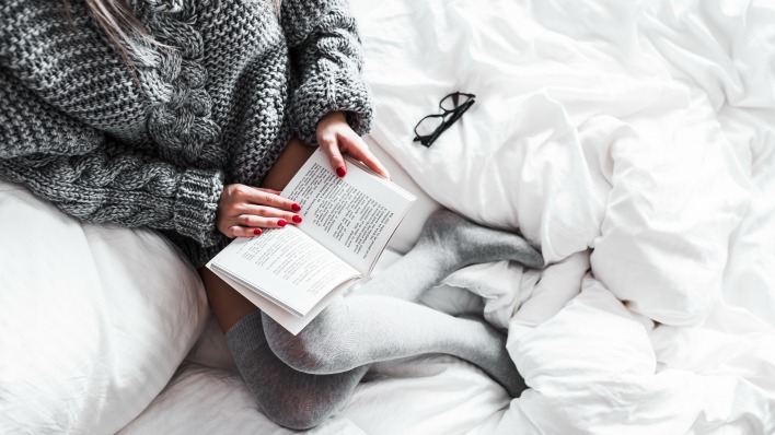 девушка читает книга постель вязаная кофта очки