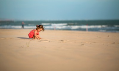 Девочка копается в песке на пляже