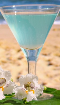 Голубой коктейль на берегу с цветками
