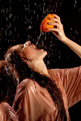 Девушки с апельсином под каплями воды