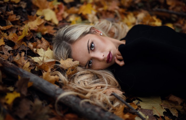 Девушка на земле в осенних листьях