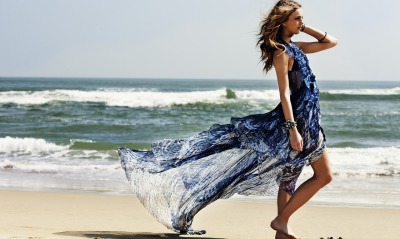 Девушка на пляже в развивающимся на ветру плье