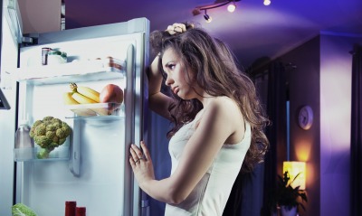 девушка в раздумьях перед холодильником