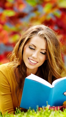 счастливая девушка с книгой на лужайке