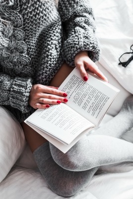 девушка читает книга постель вязаная кофта очки