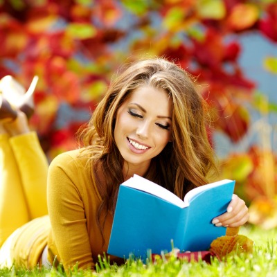 счастливая девушка с книгой на лужайке
